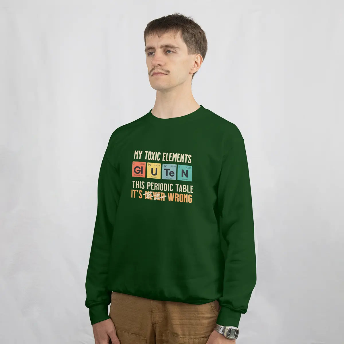 Hombre con una sudadera verde con el gráfico de la tabla periódica Mis elementos tóxicos, para celiacos